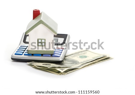 A model house sitting with a calculator and dollar