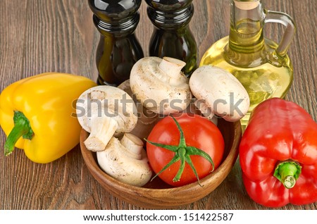 Fresh vegetables and mushrooms with olive oil and pepper shaker. Isolated on wooden