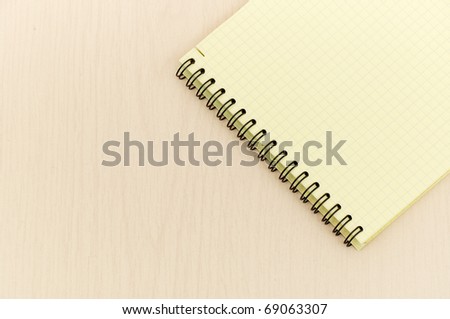 yellow note book with lots of room for your text or image on a wooden desk