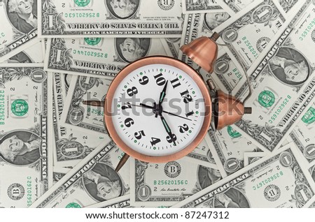 Alarm clock on a stack of dollars, reflecting time and money