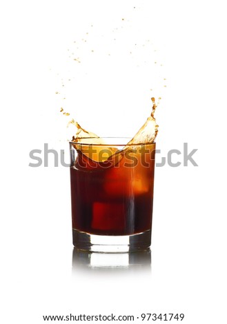 Ice cube dropped in cola glass and cola splashing