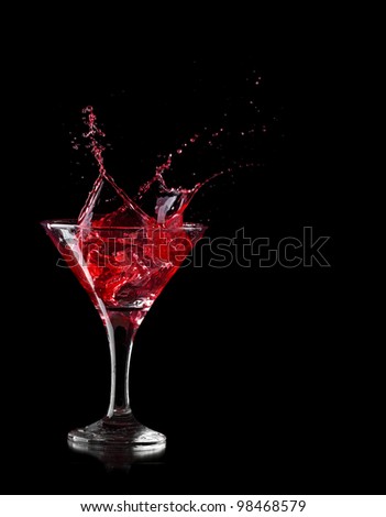 red martini cocktail splashing into glass on black background
