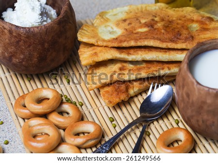 Fried pies, cheese, sunflower oil, milk and bagels on a plate close-up.