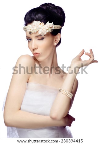 Young woman isolated on white studio background dressed in the cape of organza and beautiful tiara flirts with the viewer