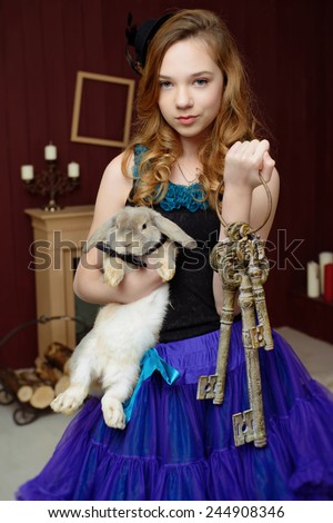 A young girl in the image of Alice in Wonderland stands near the fireplace and holds a rabbit and keys