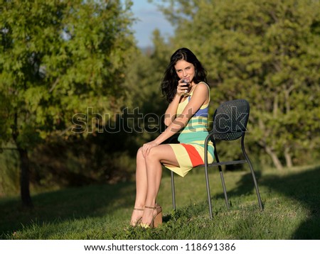 Beautiful calm young woman with glass of red wine outdoor at evening light