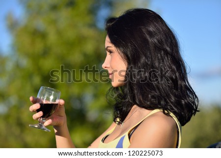 Beautiful calm young woman with glass of red wine outdoor at evening light