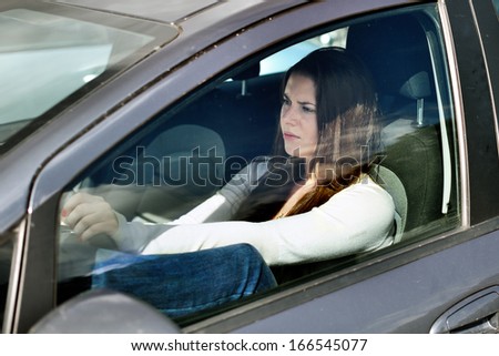 Young dissatisfied girl driving a car in traffic jam. Problems of a modern city