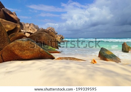 Granite rocky beaches on Seychelles islands, La Digue,Grand Anse. Big orange shell in the surf