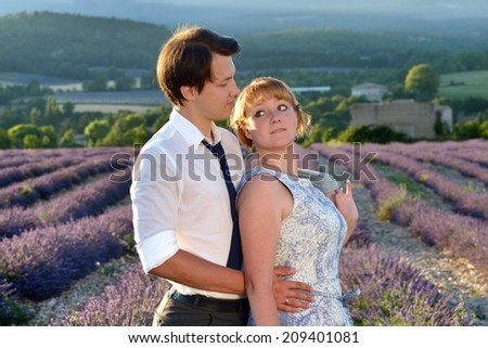 Portrait of young sensual loving couple in a lavender field at sunset backlight. Provence, France