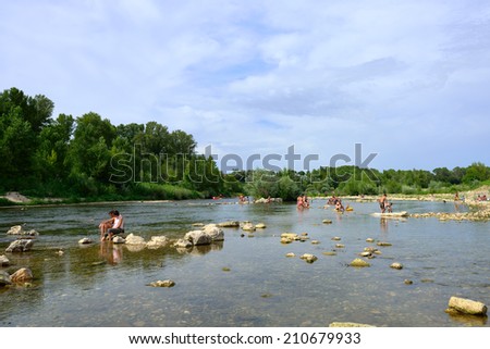 REMOULINS, FRANCE - JUL 19, 2014: Tourists have a rest on the shore of Gardon river in southern France. The Gorge du Gardon is a popular recreation area for kayaking, canoeing, and hiking