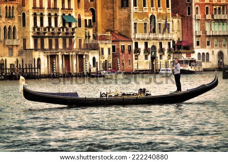VENICE - SEP 25, 2014: Gondolier rides gondola at sunset on the Grand Canal. Gondola is one of the symbols of Venice and major mode of touristic transport in Venice, Italy.