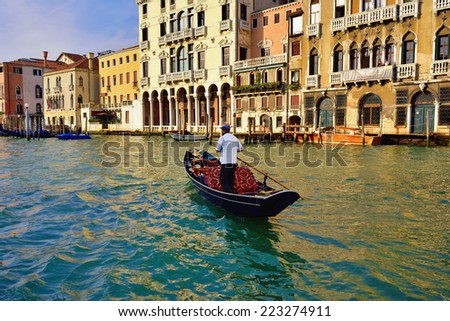 VENICE - SEP 24, 2014: Gondolier rides gondola on the Grand Canal at sunset. Gondola is one of the symbols of Venice and major mode of touristic transport in Venice, Italy.