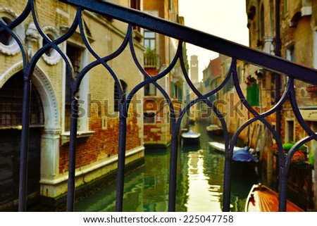 View on the Venice water canal through the bars of the bridge at sunset
