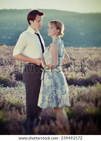 Portrait of young sensual loving couple in a lavender field at sunset backlight. Provence, France. Filtered image, cross processing from RAW file and vintage affect applied