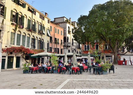 VENICE, ITALY - SEPT 21, 2014: People visit street cafe on square in Venice at evening time. This is the typical Venetian cafe