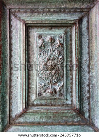 Background of ancient copper bas-relief coated with a green patina