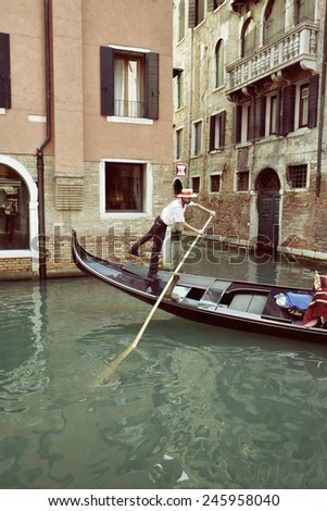 VENICE - SEP 25, 2014: Gondolier rides gondola on a water canal. Gondola is one of the symbols of Venice and major mode of touristic transport in Venice, Italy. Filtered image, vintage effect applied