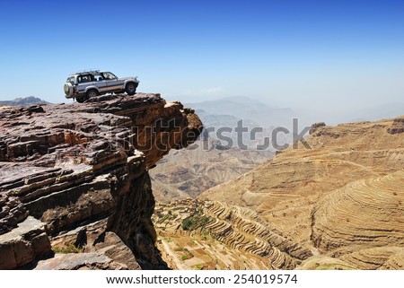 YEMEN - MARCH 13, 2010: Off-road vehicle on the edge of a steep cliff over breakaway at plateau Bokur (800m high). Extreme mountain safari is one of the main local tourist attraction in Yemen