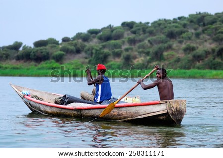 UGANDA - AUG 29, 2010: Two fishermen in a boat moving on the Nile at twilight. The Nile river is the only source of transportation in this region of central Africa
