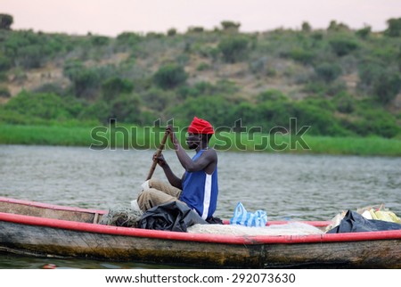 UGANDA - AUG 29, 2010: Fisherman in a boat moving on the Victoria Nile at twilight. The Nile river is the only source of transportation in this region of central Africa
