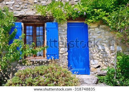 France, Provence. Typical old house, open window with the blue shutters and blue door surrounded a green plant