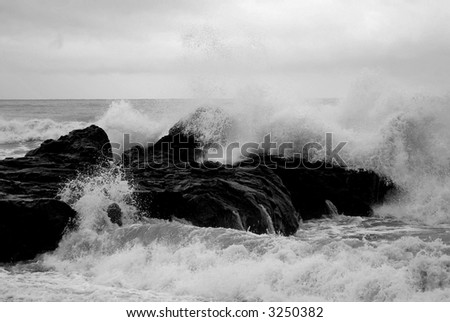 Black and white of ocean waves breaking on coastal rocks