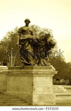Sepia tone statue of lion and lady in front of Buckingham palace London