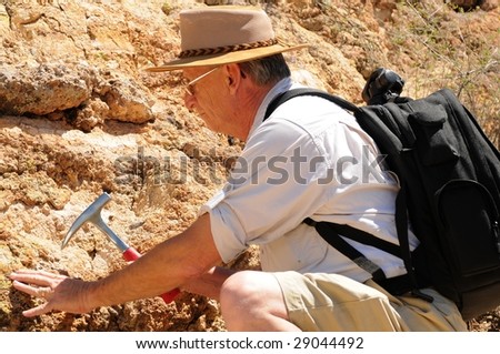 Senior geologist tap a rock formation with a hammer