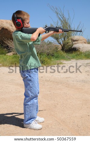 Young boy in the desert shooting a rifle