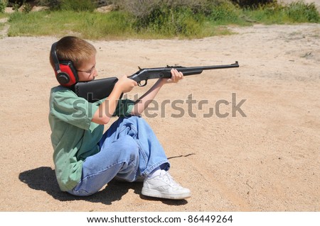 Young boy in sitting position shooting a rifle