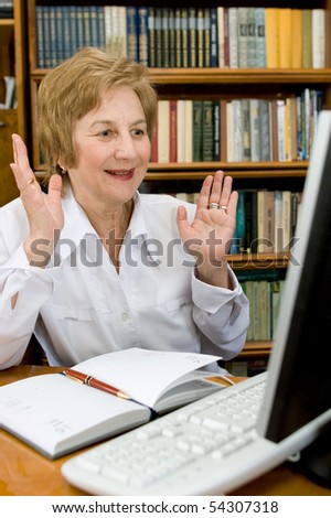 Elderly woman business-lady works at computer.  a pleased smile upon one\'s face