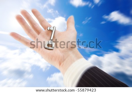 Key to success. The businessman holds the key against the blue sky.