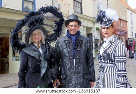 WHITBY, ENGLAND - APRIL 27: Man and two women in Goths attire are enjoying their participation at Whitby Gothic Weekend, one of the most popular Gothic events in the world.  Whitby 27, April 2013.