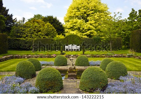 Formal garden with white wooden bench and topiary shrubs.
