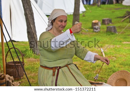 TATTON PARK, ENGLAND - JUNE 15: Woman in medieval costume spinning yarn, participant at The Medieval Fayre one of the most popular annual events of the Tatton Park in Cheshire, 15, June 2013.