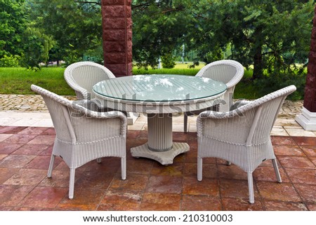 White table and chairs patio furniture in a garden\'s gazibo.