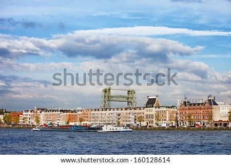 Terraced apartment houses along the  river in Rotterdam city centre, Netherlands, Queen\'s Bridge (Dutch: Koninginnebrug) in the background.