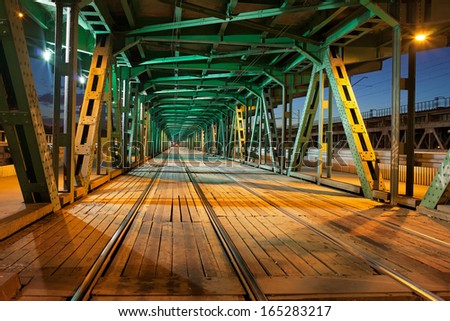 Tramway with two tracks in the lower part of the steel truss Gdanski Bridge in Warsaw, Poland, night illumination, vanishing point perspective.