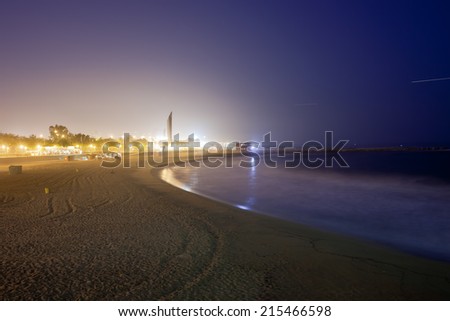 Glow from the city at night illuminates the sky and sea at Icaria beach in Barcelona, Catalonia, Spain.