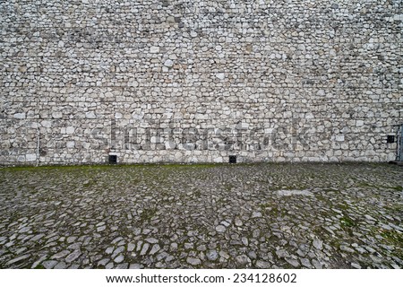 Medieval castle wall and cobbled square background, made of stone in 14th century.