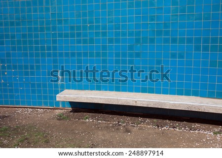 Wall with blue tiles and concrete bench near the sea.