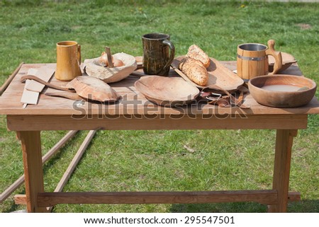 Table outside on a meadow with traditional wooden and ceramic dishes, bowls, beer mugs, tray, plates, spoon