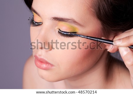 stock photo : Applying professional makeup on young woman face. Shallow depth of field.