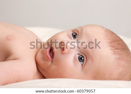 Ten weeks old cute little baby girl with curious look on her face lying comfortably on bed