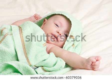 Ten weeks old cute little baby girl toddler wrapped in towel stretching her arm