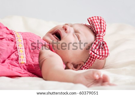 Crying ten weeks old baby girl on bed