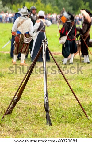 Two historical rifles on the field, out of focus soldiers in the background