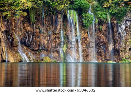 Waterfall with reflection on lake waters, Plitvice Lakes National Park in Croatia.