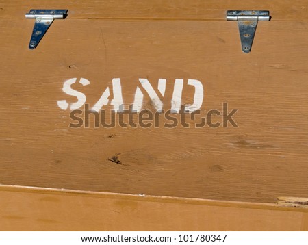 Hinged lid of painted plywood box providing sand to prevent slippage in winter conditions.